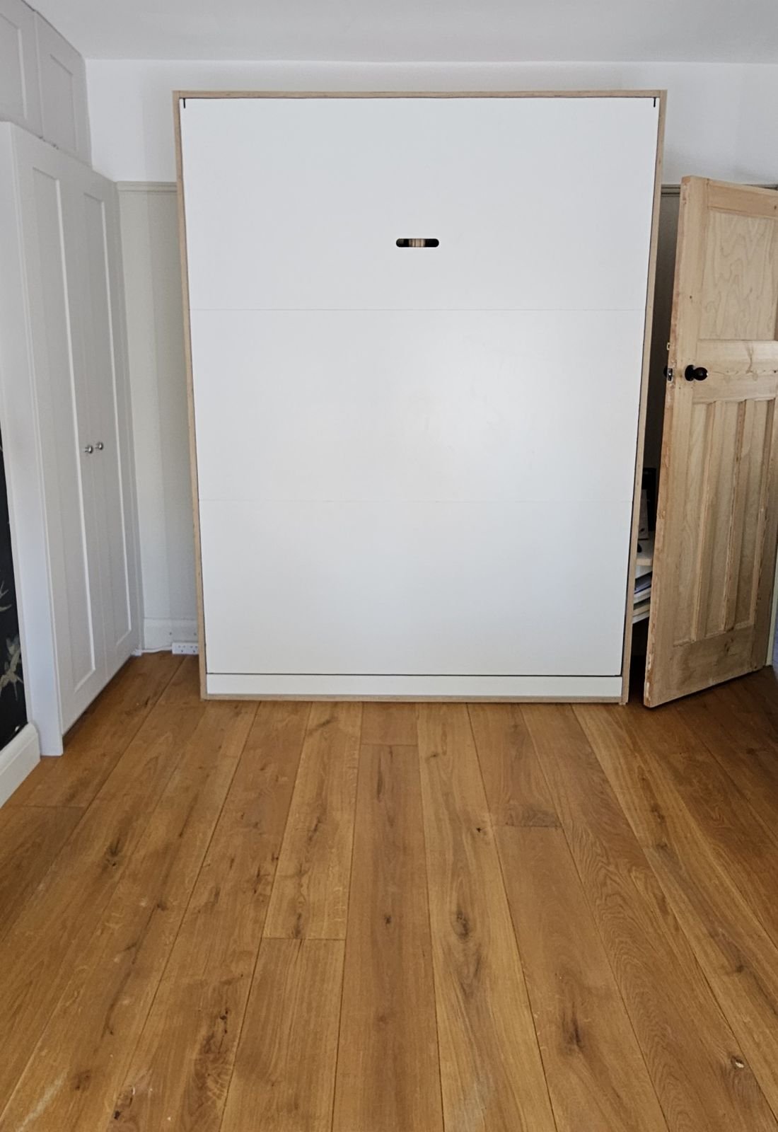The folding bed closed against the wall, leaving the floor clear