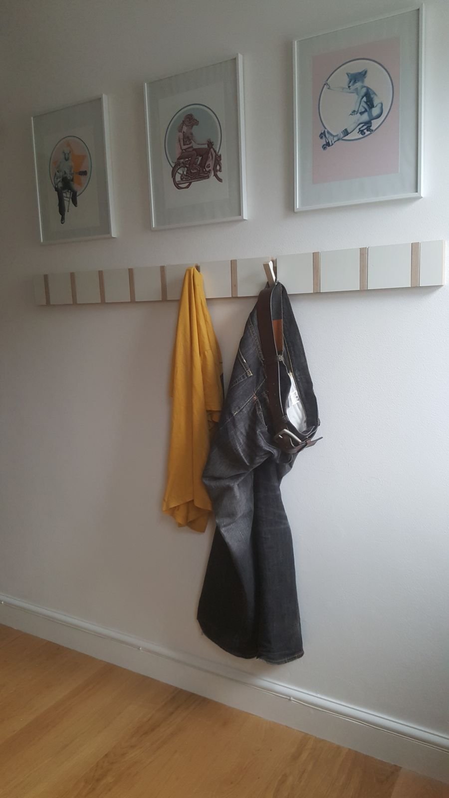 The hook board on a wall with a couple of coats hung up