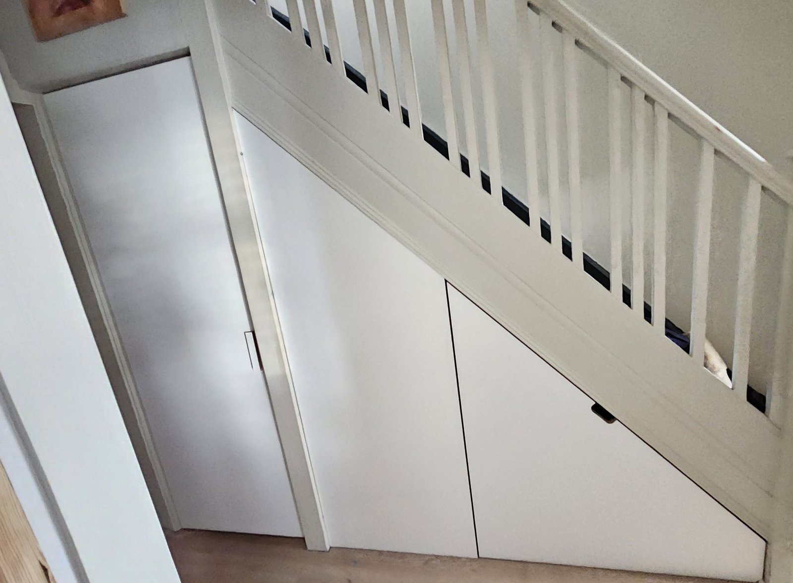 The white ply wall under the stairs with the toilet door on the left and the drawer front on the right