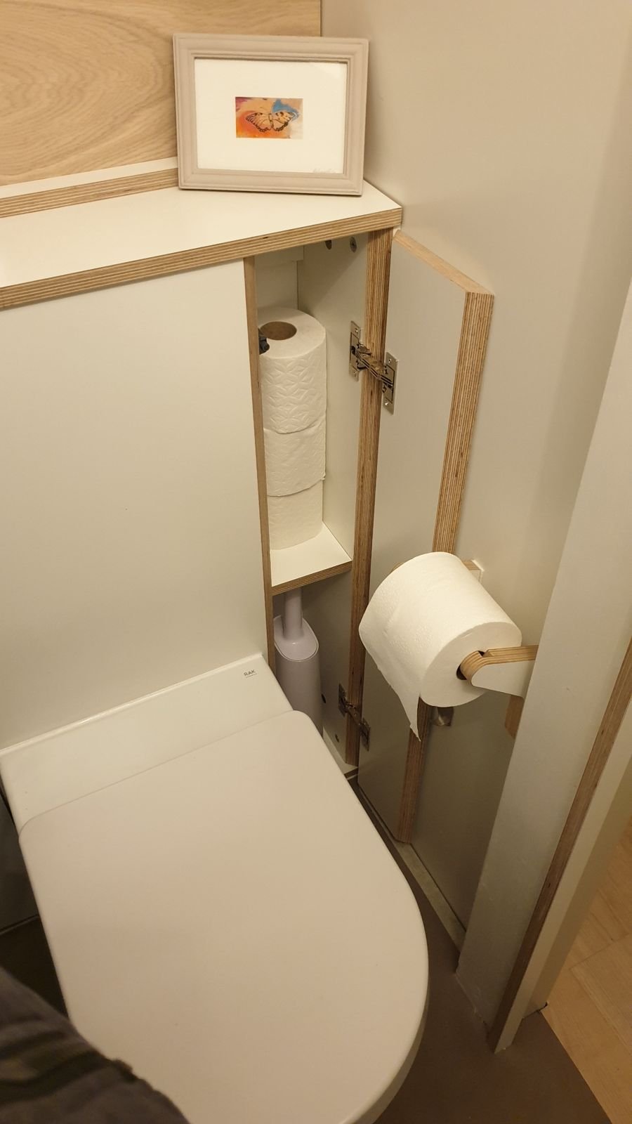 Door open on the side cupboard with spare toilet rolls