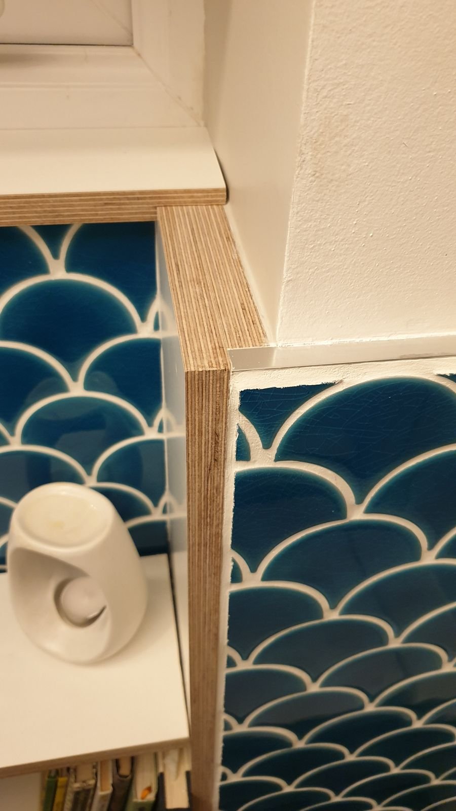 Close-up of a plywood shelf edge against the tiles